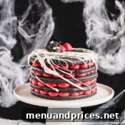 A 5-layer black macaron cake filled with red cream cheese filling on a white cake stand, highlighting the spooky aesthetic.