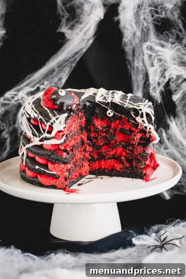 A slice of the 5-layer black macaron cake with red cream cheese filling and marshmallow spiderweb removed, revealing its impressive layers and delightful interior.