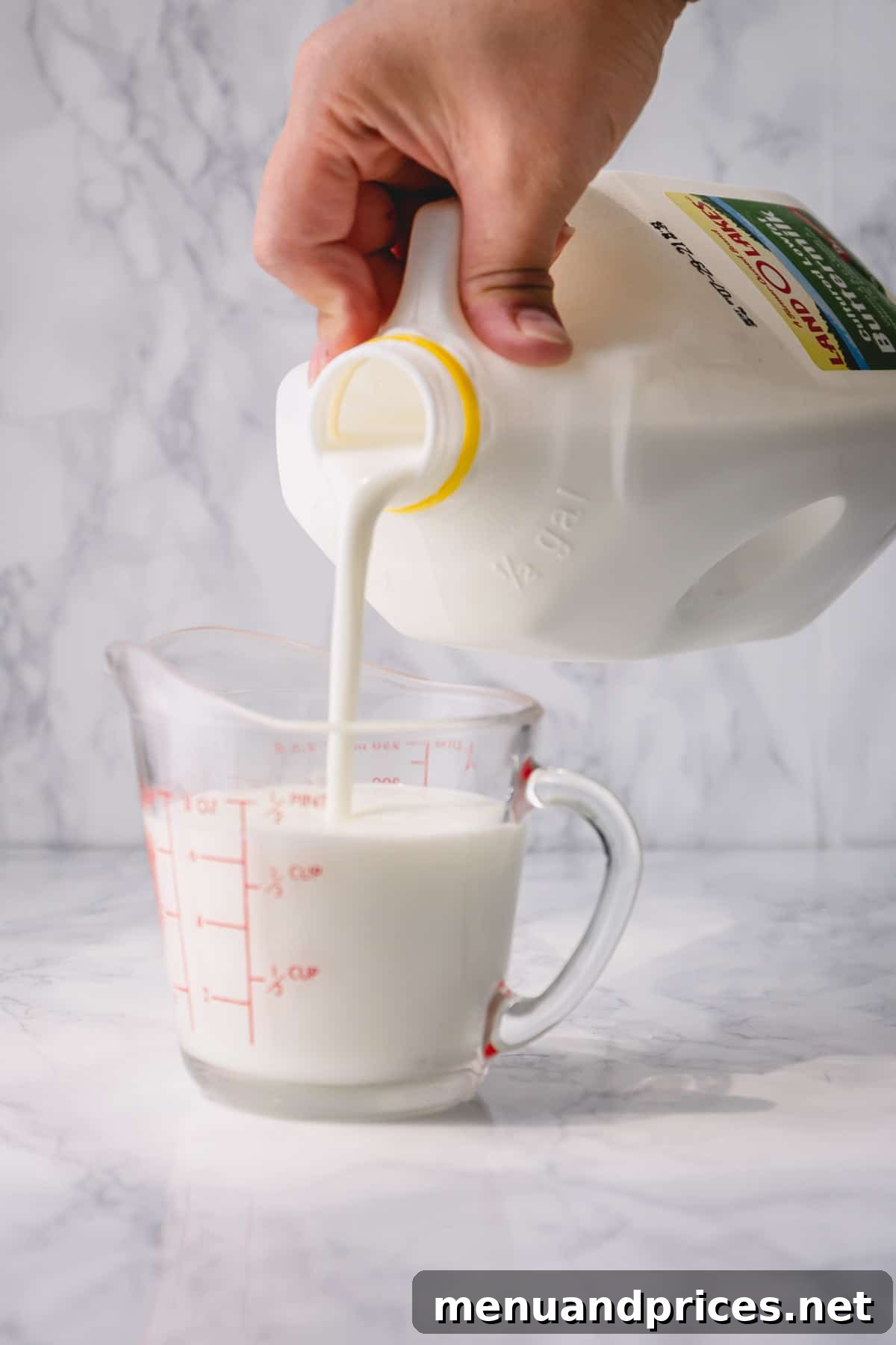 Buttermilk substitute being poured into a measuring cup, ready for use in a recipe.