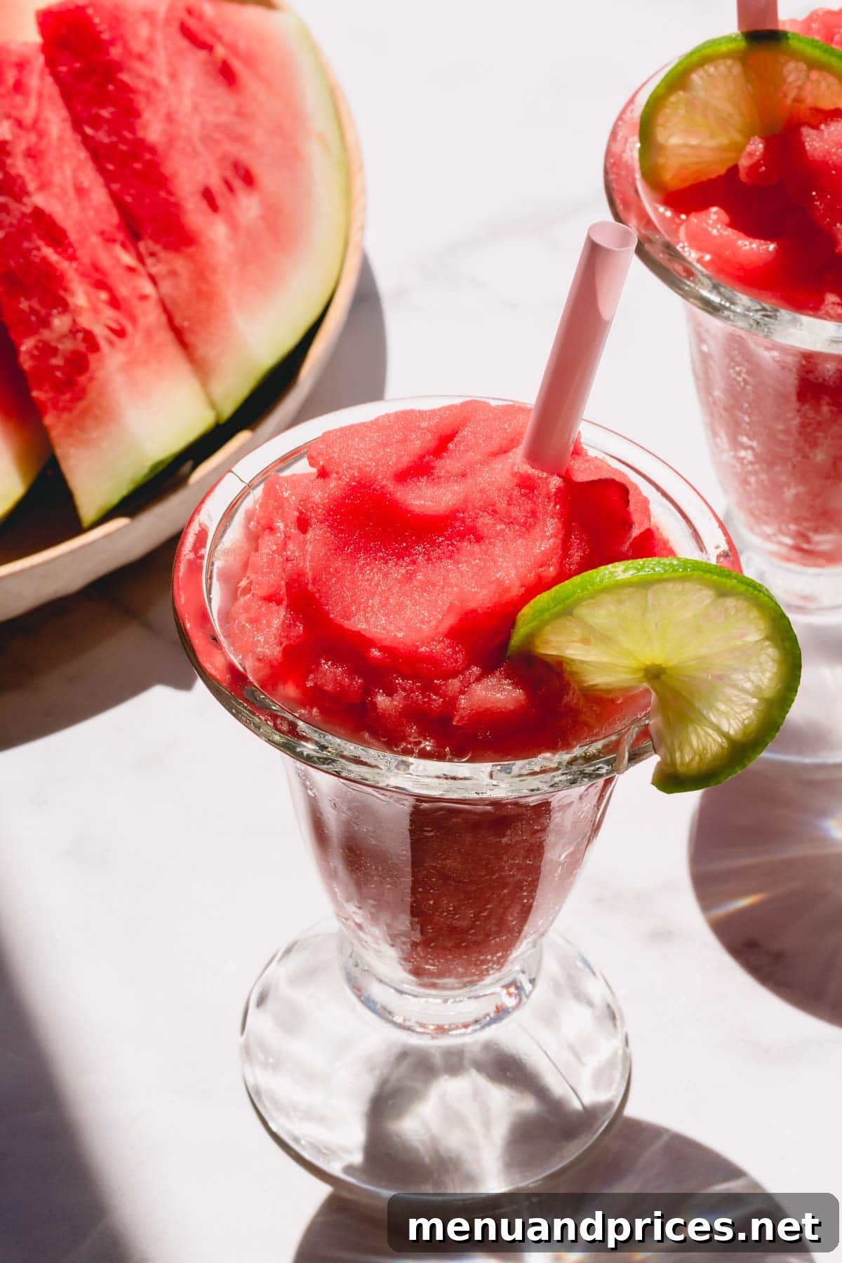 Crimson Wave Daiquiri 2 A glass of frozen watermelon daiquiri garnished with a slice of lime.