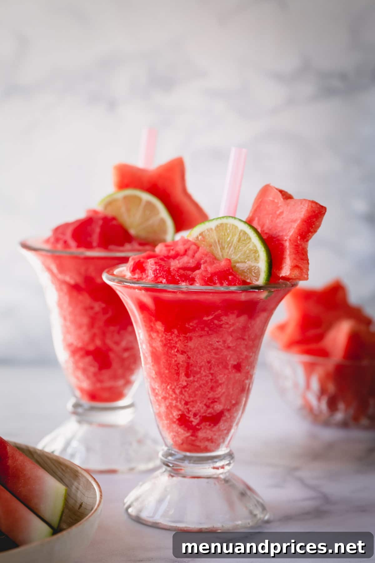 Crimson Wave Daiquiri 5 2 glasses of frozen watermelon daiquiri garnished with slice of lime and watermelon star.