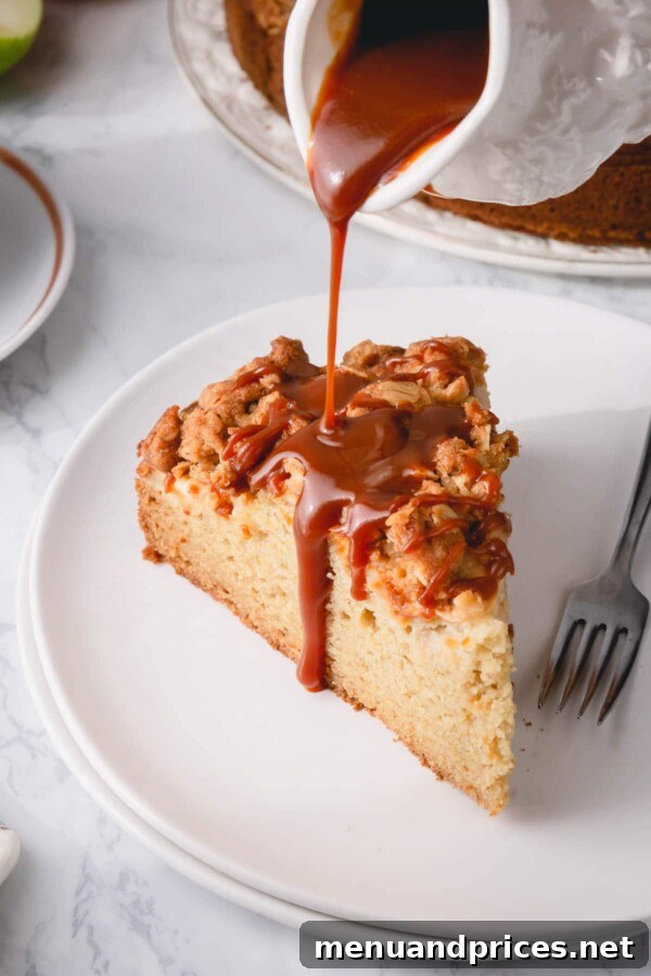 Spiced Apple Streusel Coffee Cake 11 A tantalizing slice of apple coffee cake on a white plate, with luxurious caramel sauce being poured over it, highlighting its moistness.