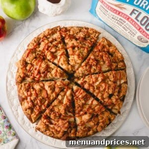 Overhead image of sliced apple coffee cake drizzled with caramel sauce on a white serving plate, highlighting its appetizing appeal.