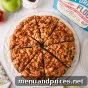 Overhead image of a delightful slice of apple coffee cake, artfully drizzled with caramel sauce, presented on a white serving plate, inviting a taste.