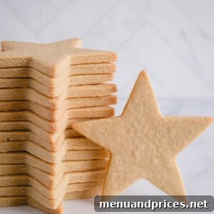 One large star shaped sugar cookie standing against a stacked cookies.