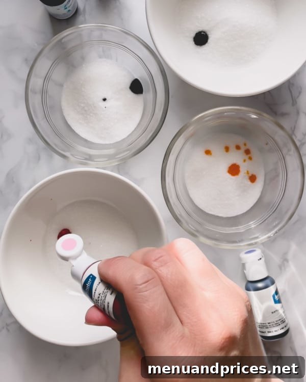 Whip Up Vibrant Homemade Sugars 4 Bowls of granulated sugar with small droplets of gel food coloring added, ready for mixing.