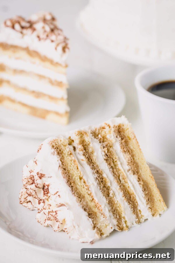 Decadent Tiramisu Dream Cake 3 A perfectly cut slice of Tiramisu Layer Cake resting on a pristine white plate, showcasing its beautiful layers of sponge and cream.
