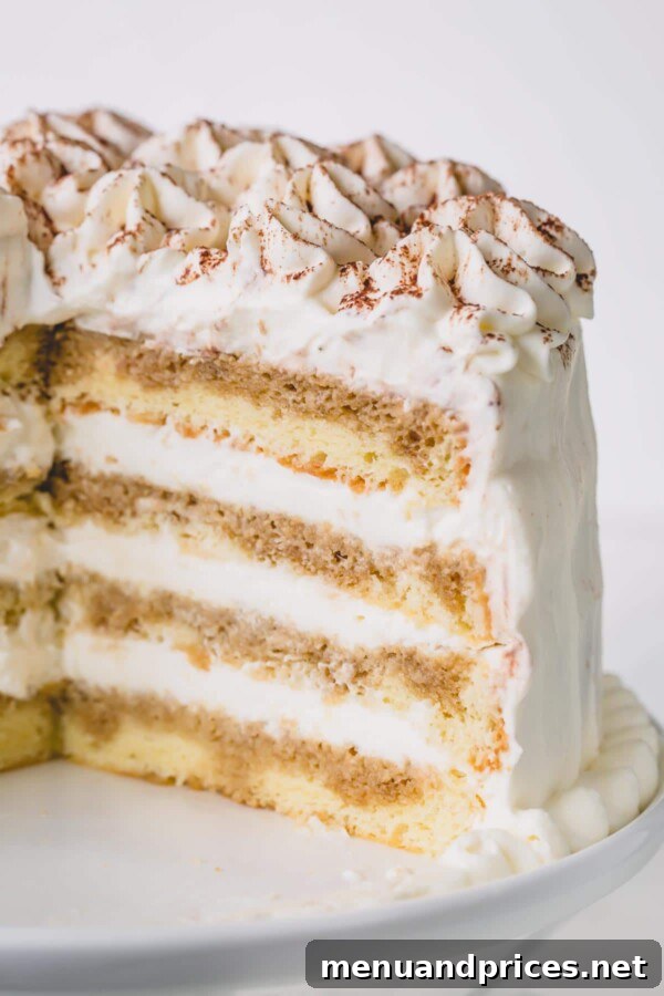 Decadent Tiramisu Dream Cake 5 A beautifully cut Tiramisu Layer Cake on a white cake platter, showing multiple delicate layers.