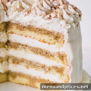 A cut version of a whole tiramisu layer cake on a white cake platter, ready to be enjoyed.