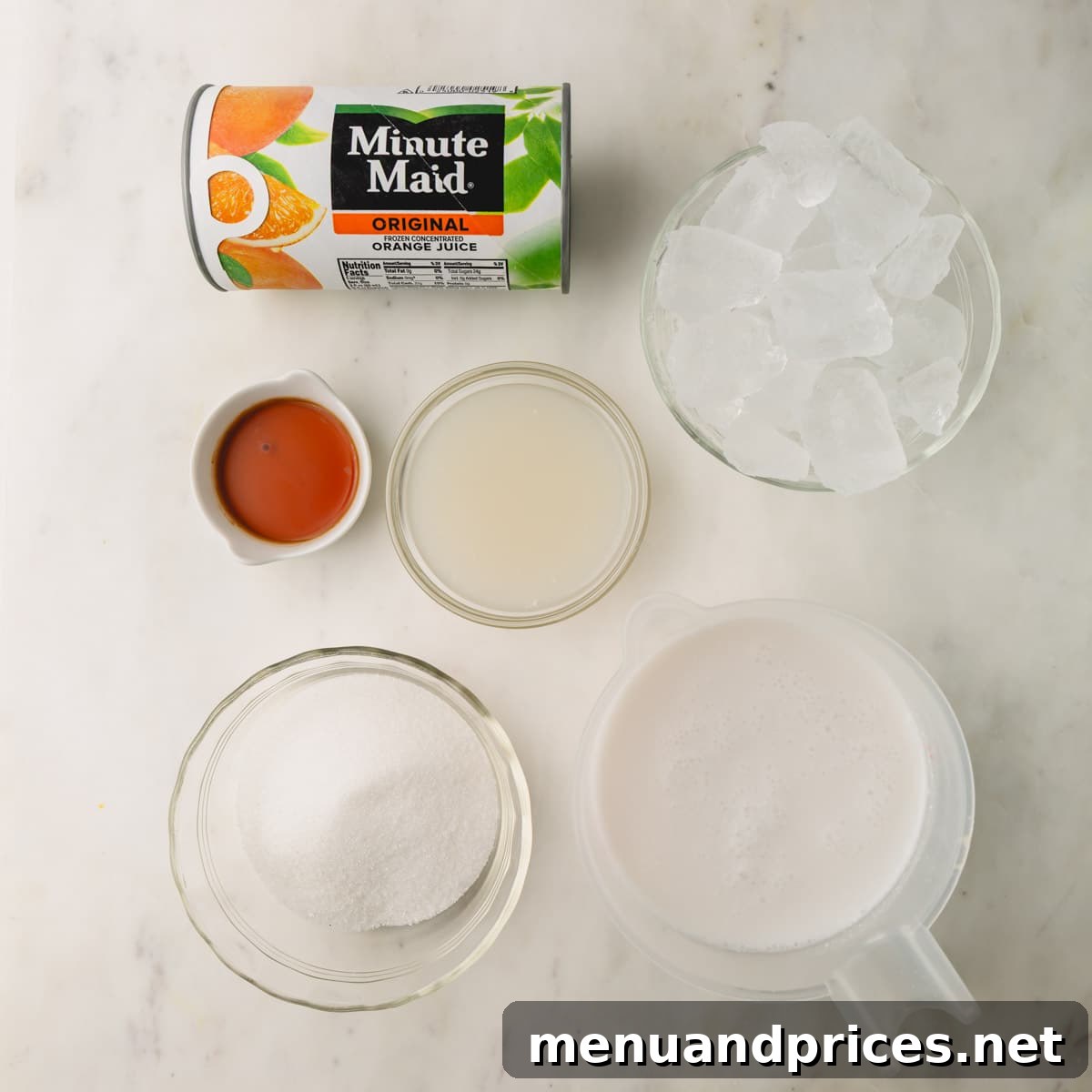 Creamy Vegan Coconut Orange Dream 3 Assortment of fresh ingredients laid out for making a coconut orange Julius drink, including orange concentrate, coconut milk, sugar, vanilla, and cream of coconut.