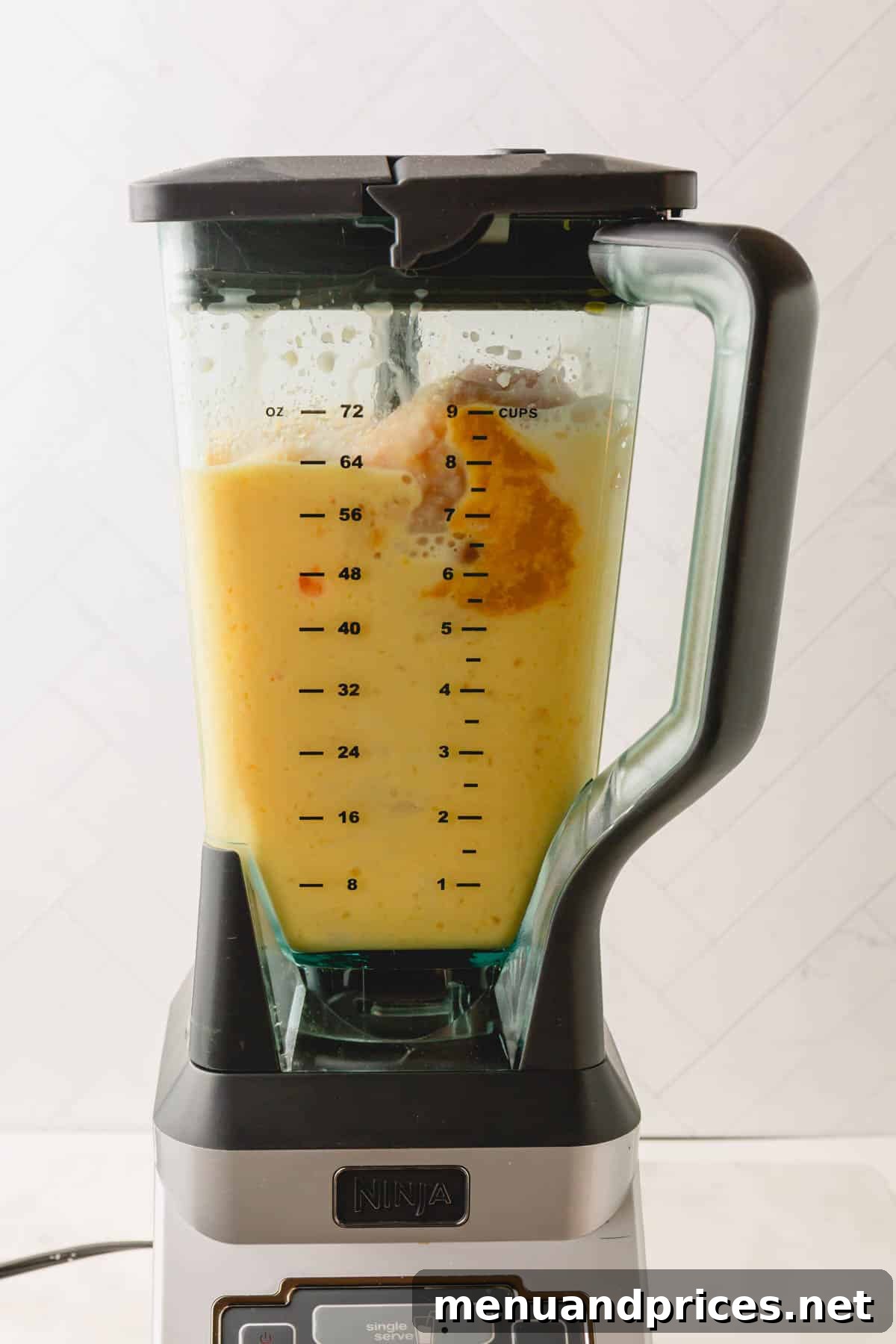 Creamy Vegan Coconut Orange Dream 5 A blender containing the creamy, orange-hued coconut orange Julius drink mixture, ready to be poured.