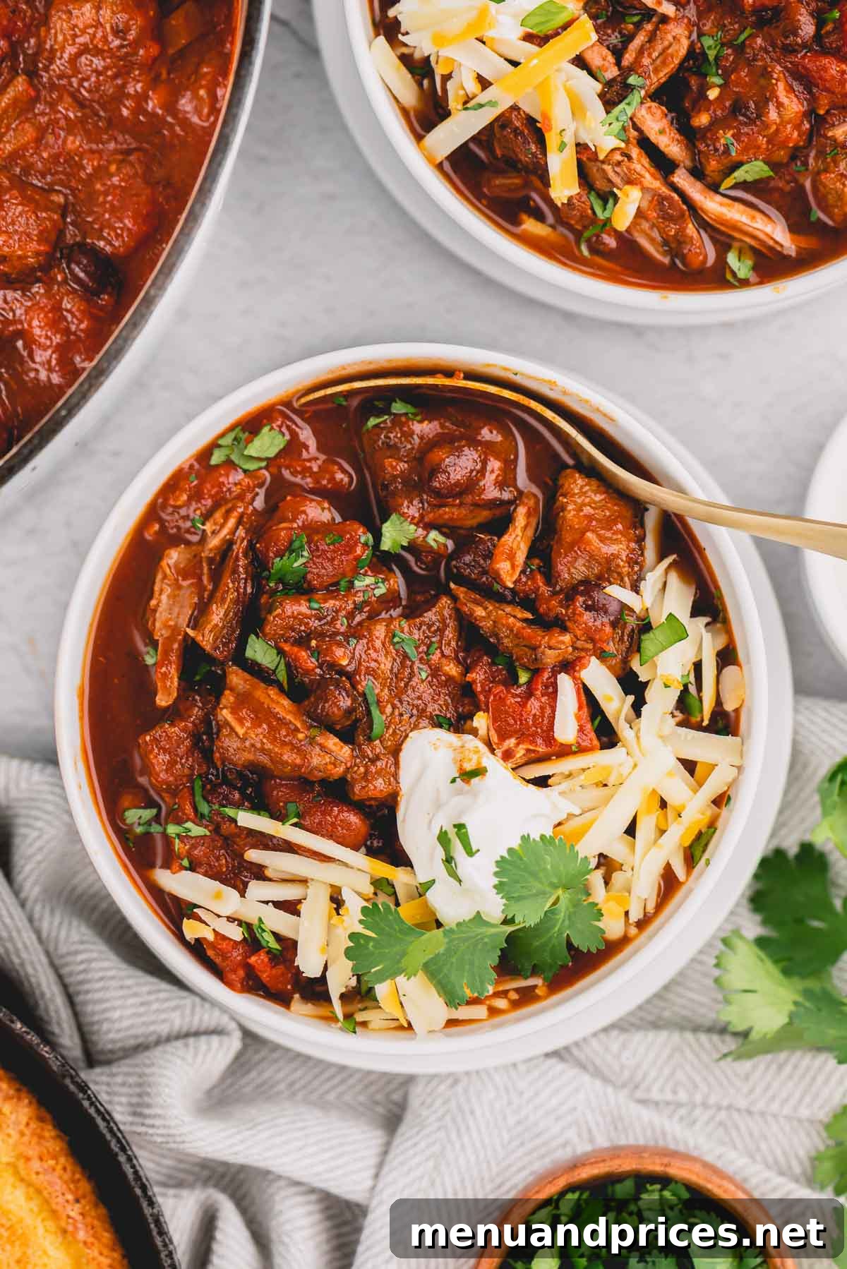 Hearty Chunky Beef Chili 8 chunky chili in a bowl topped with cheese, sour cream and cilantro.