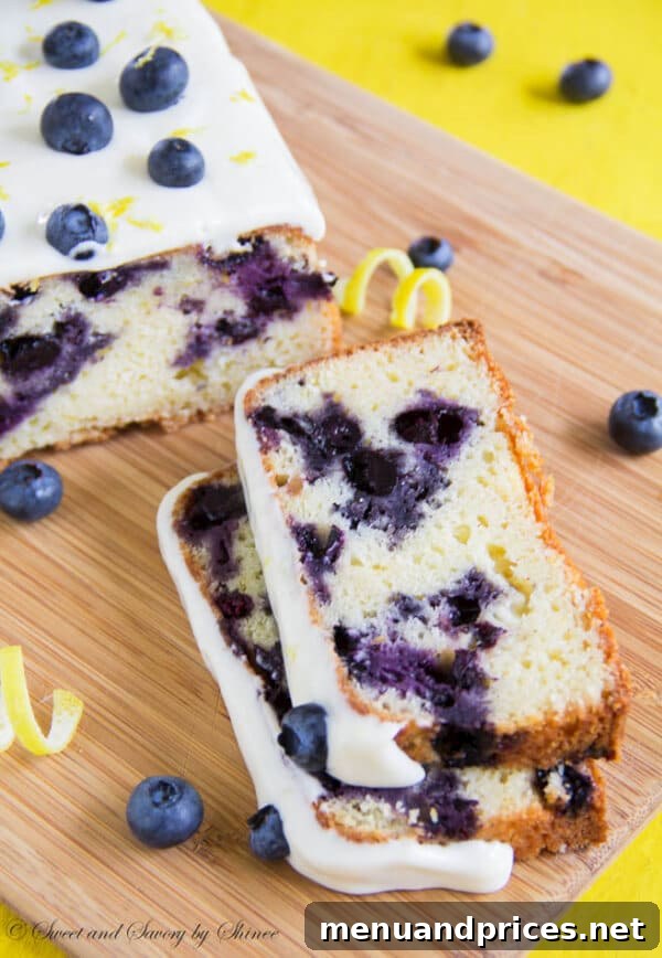 Zesty Blueberry Lemon Delight 2 A beautifully glazed blueberry lemon cake, sliced to reveal plump blueberries inside, sitting on a white serving plate.