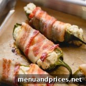 Cooked bacon jalapeno poppers on a baking sheet, showcasing their golden crispiness.