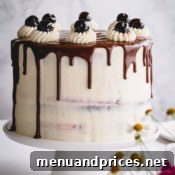 Black Forest cake with chocolate drizzle on a white cake platter.