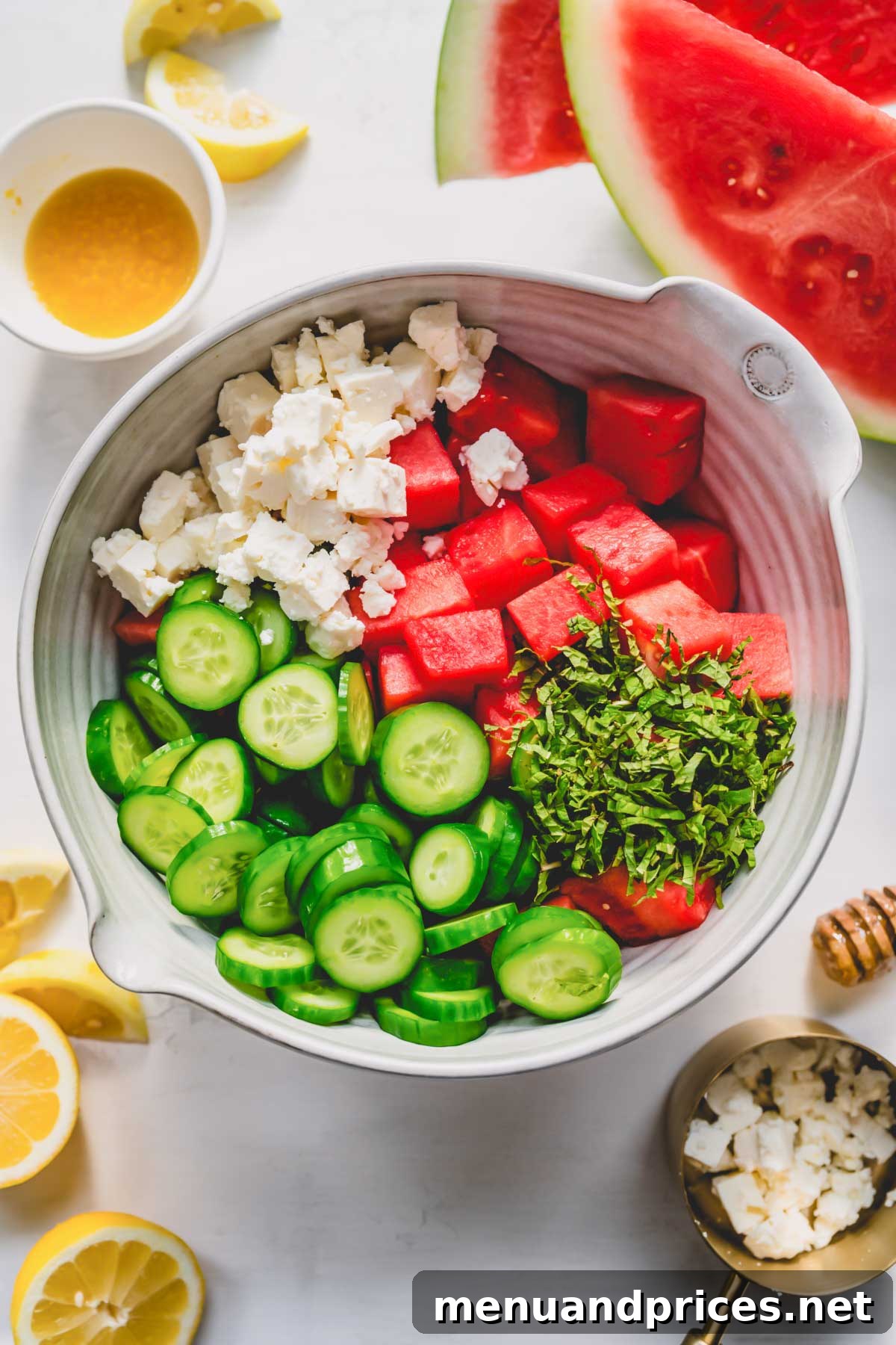 Summer Watermelon Feta Medley 5 Fresh watermelon, cucumber, feta, and mint combined in a large mixing bowl, ready to be dressed.