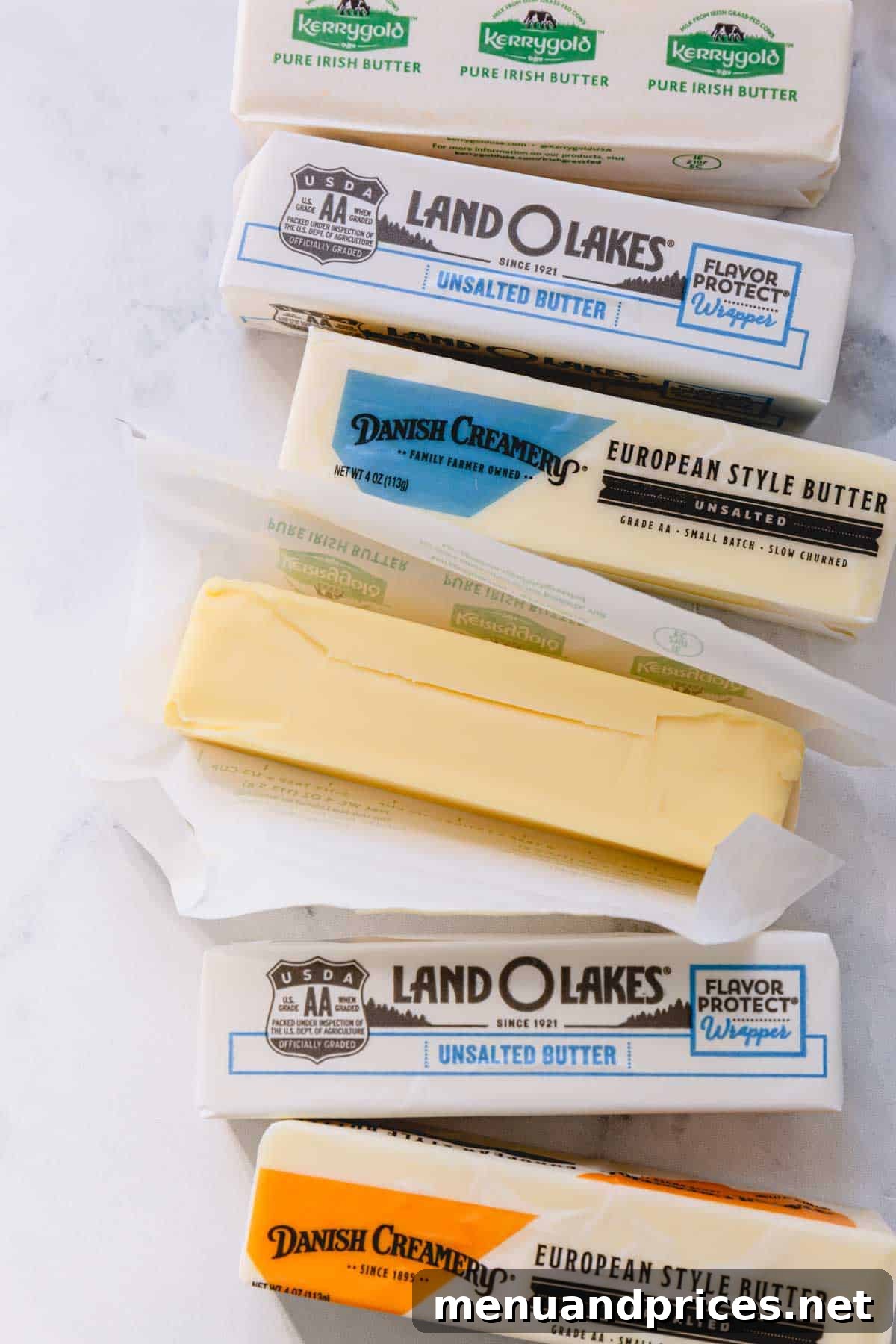 Butter Fundamentals 3 Six sticks of butter from various brands, with one unwrapped to reveal its golden texture.