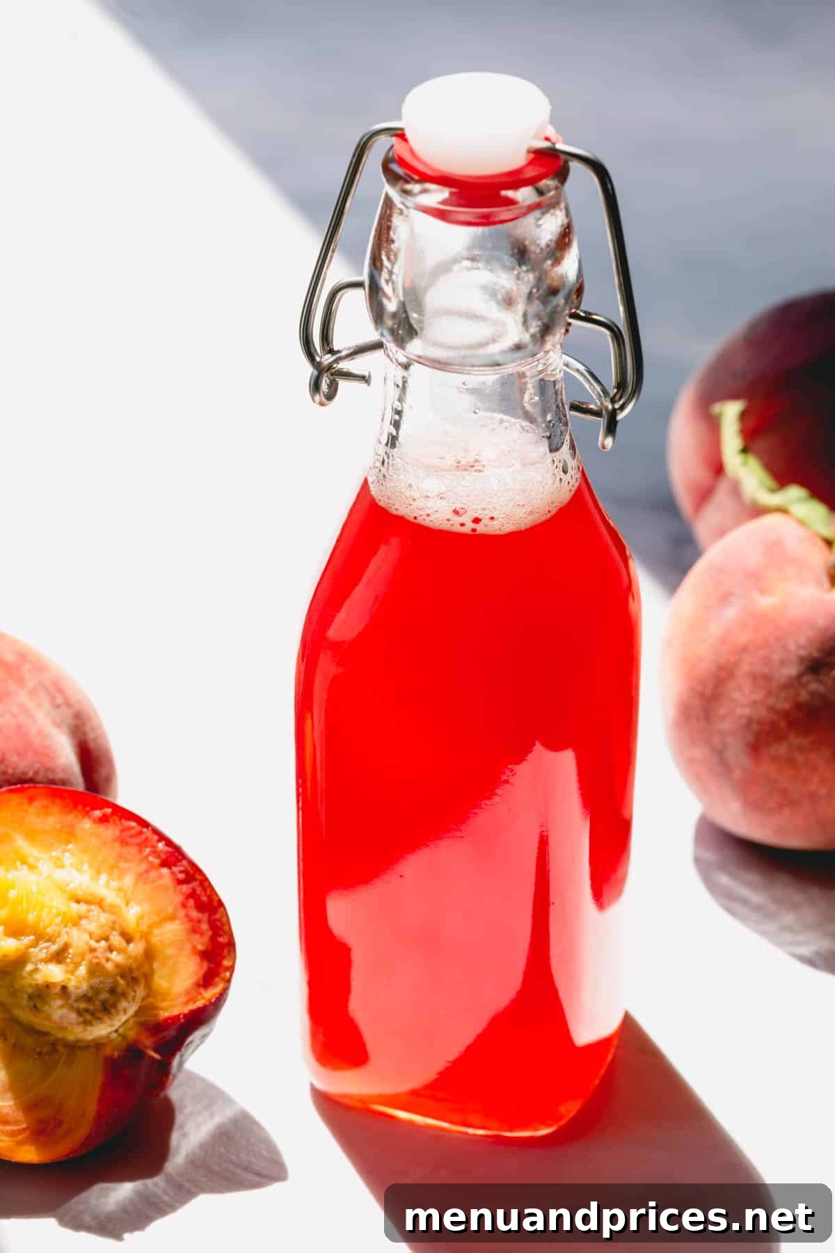 A bottle of homemade peach simple syrup with fresh peach slices in the background, showcasing its vibrant color and appeal.
