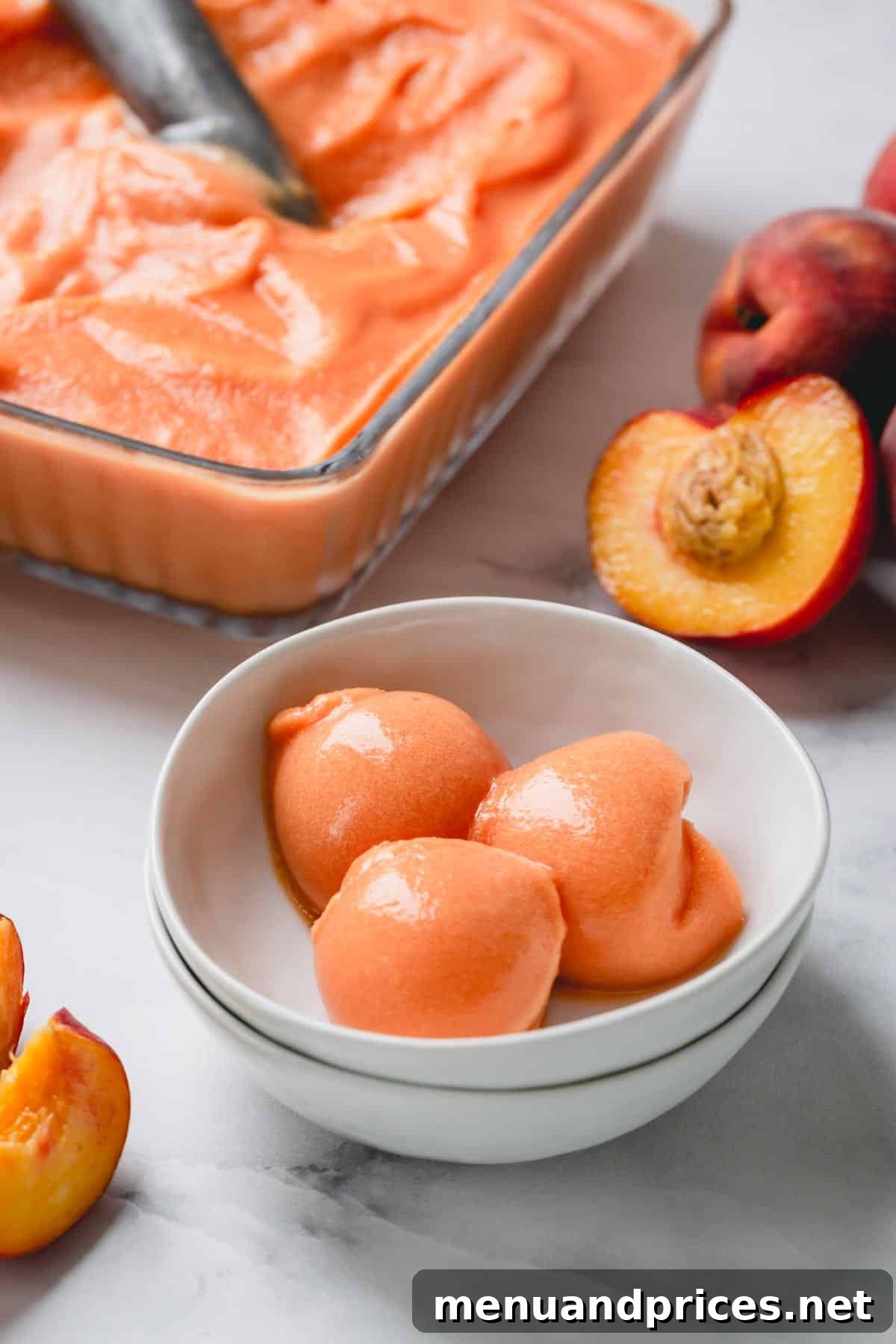 Velvet Peach Dream 6 3 scoops of peach ice cream in a white bowl, garnished with a fresh mint sprig.