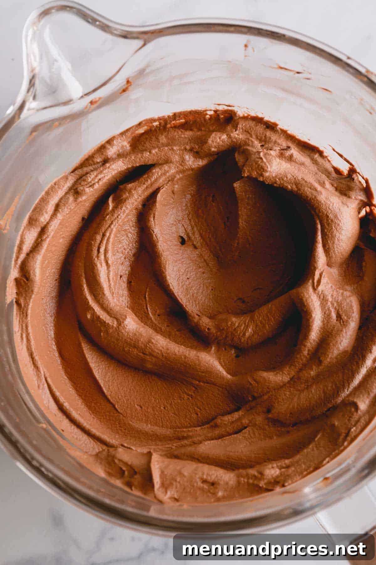 Silky Chocolate Mousse Delight 2 A glass mixing bowl overflowing with rich chocolate mousse frosting, ready for use.