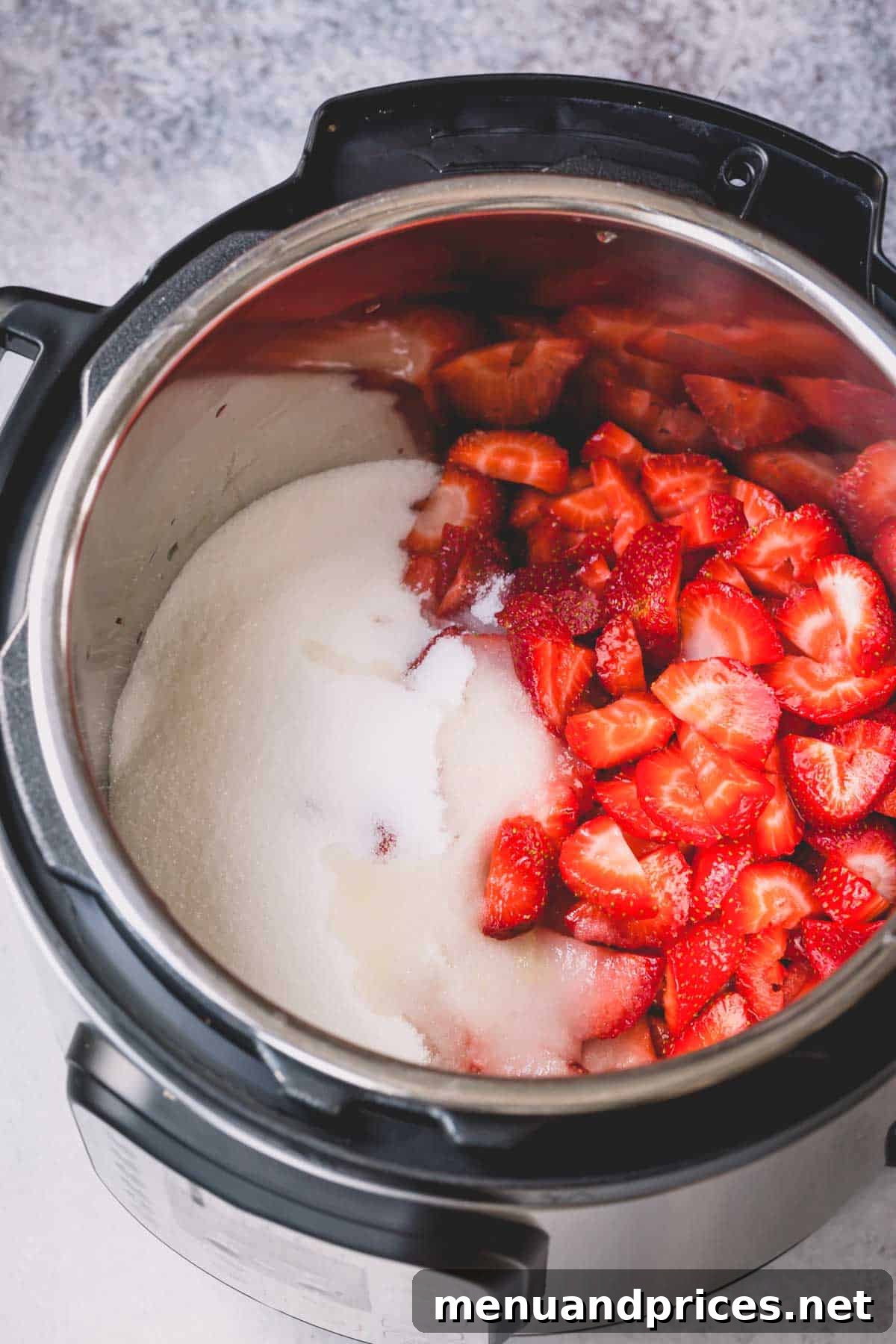 Sliced strawberries mixed with sugar and lemon juice in an Instant Pot, macerating.