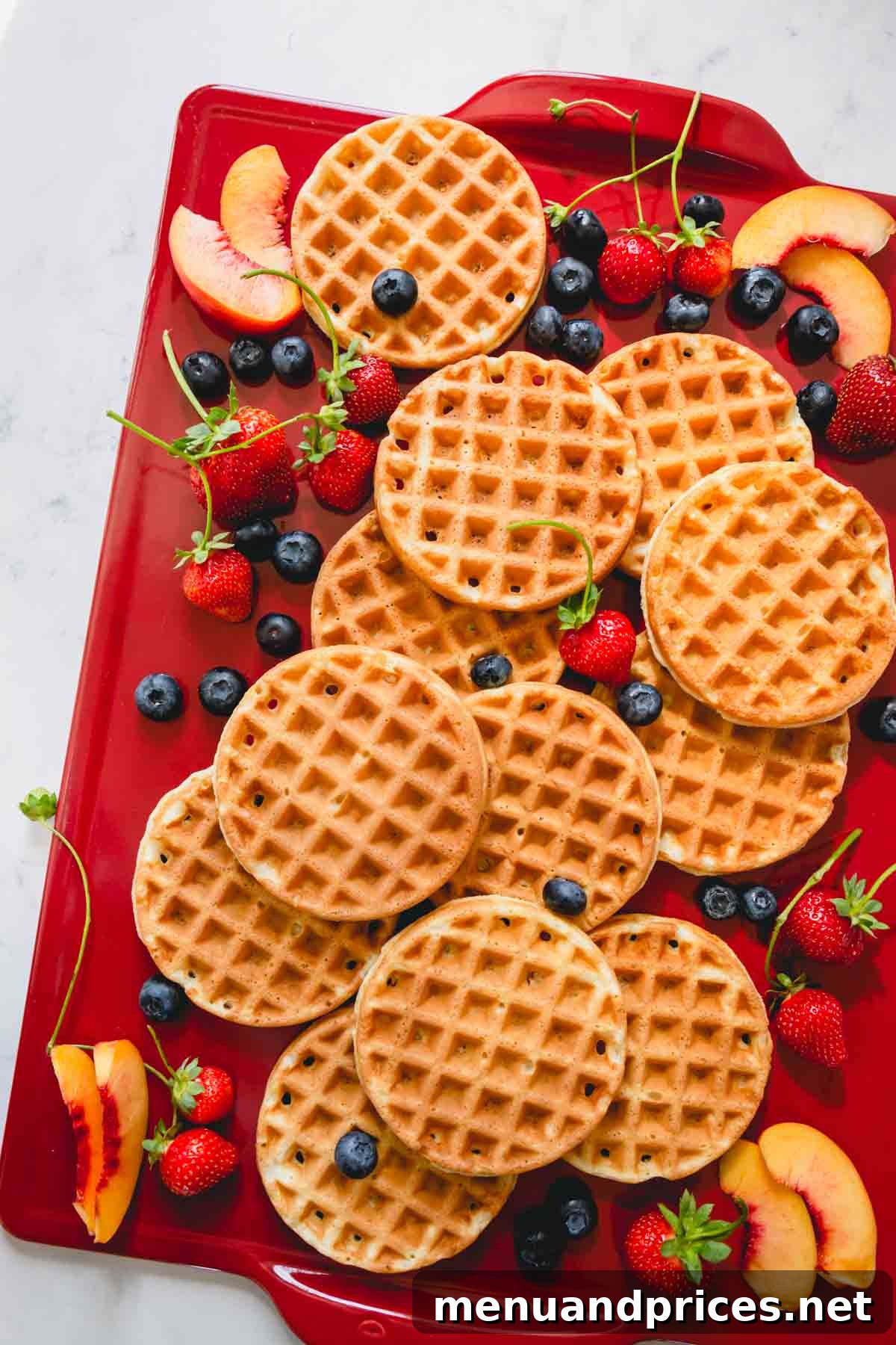 Golden Crispy Waffles 8 A charming presentation of golden-brown waffles artfully arranged on a rustic red serving board, accompanied by fresh, vibrant berries and a drizzle of syrup.