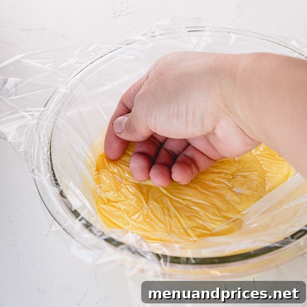 Mastering Classic French Pastry Cream 10 Custard in a bowl, properly covered with plastic wrap touching the surface.