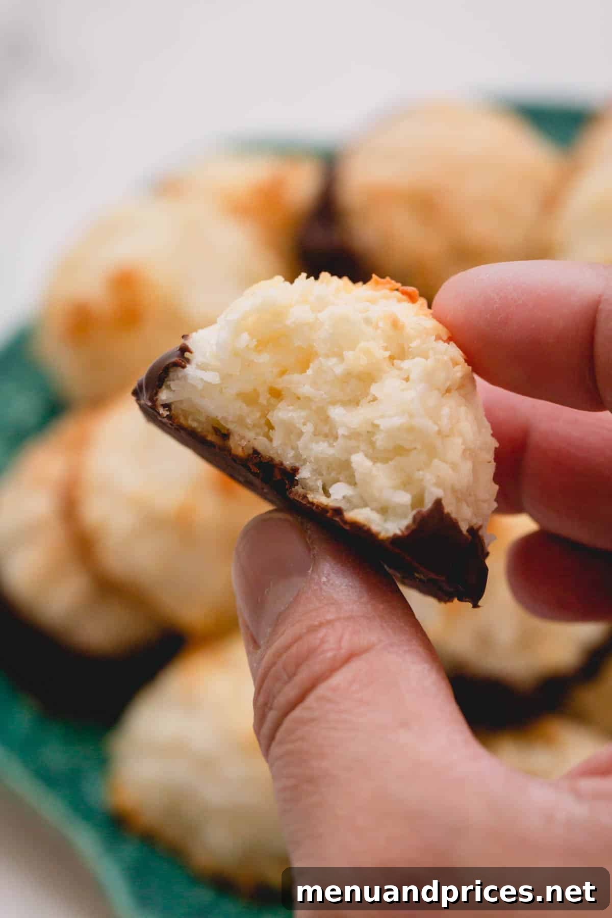 Ultimate Coconut Macaroons 3 A hand gently holding a single, perfectly baked coconut macaroon, highlighting its golden texture.