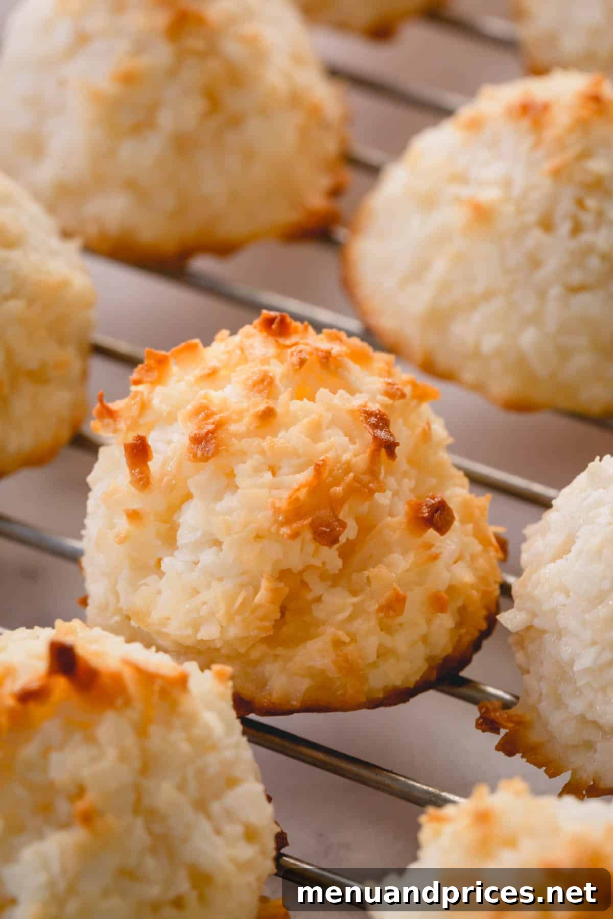 Ultimate Coconut Macaroons 9 A stack of perfectly baked coconut macaroons, some plain and some chocolate-dipped, arranged invitingly on a wire rack.