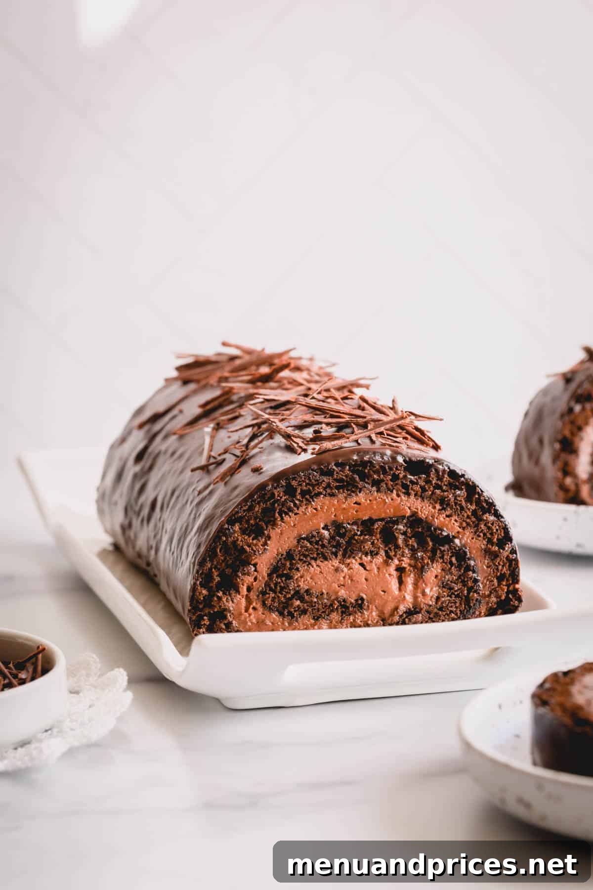 Sinful Chocolate Roll Cake 12 A delectable chocolate swiss roll presented elegantly on a white plate, showcasing its appealing spiral layers and ganache topping.