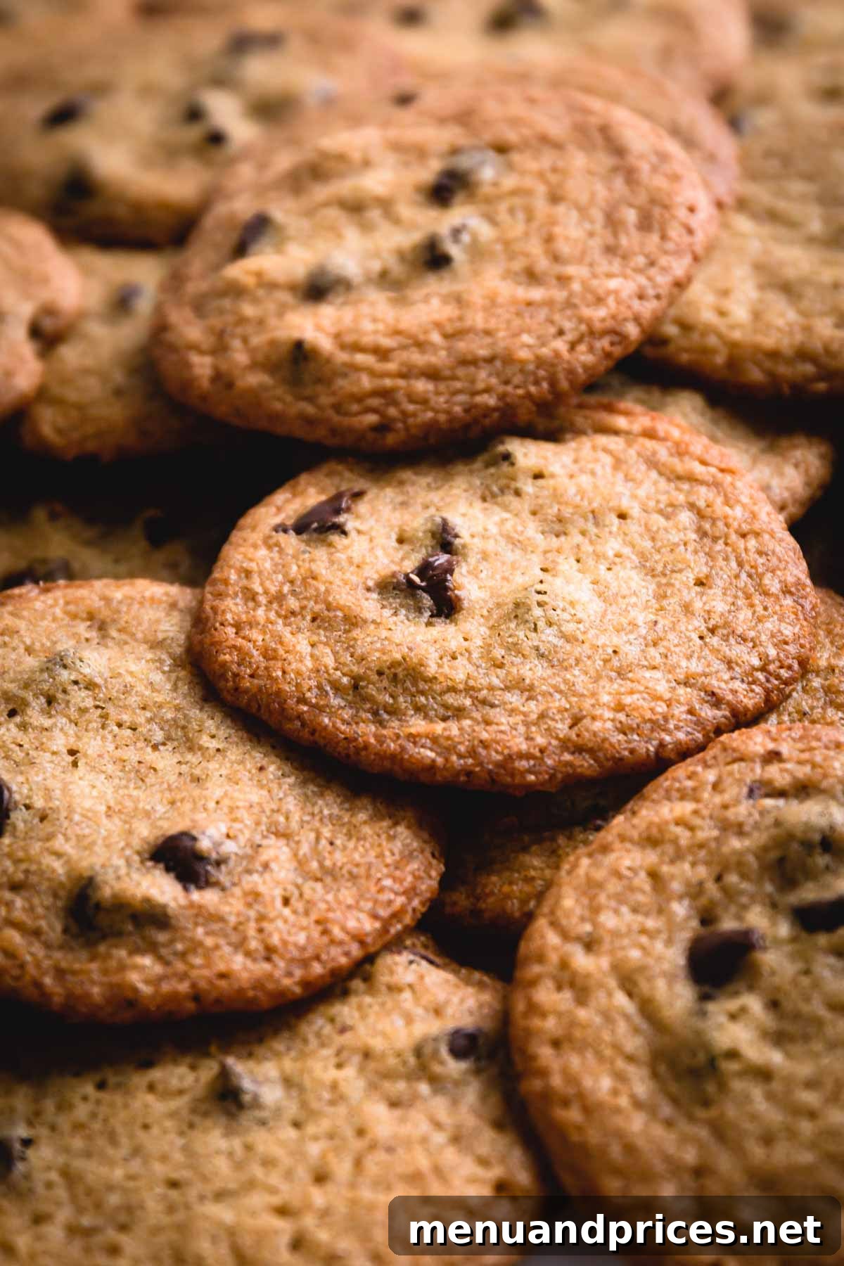 Golden Crunch Chocolate Chip Delights 2 A generous pile of golden-brown thin chocolate chip cookies, stacked to showcase their delicate crispness.