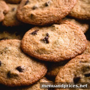 A beautiful pile of thin chocolate chip cookies, showcasing their perfect texture and golden hue.