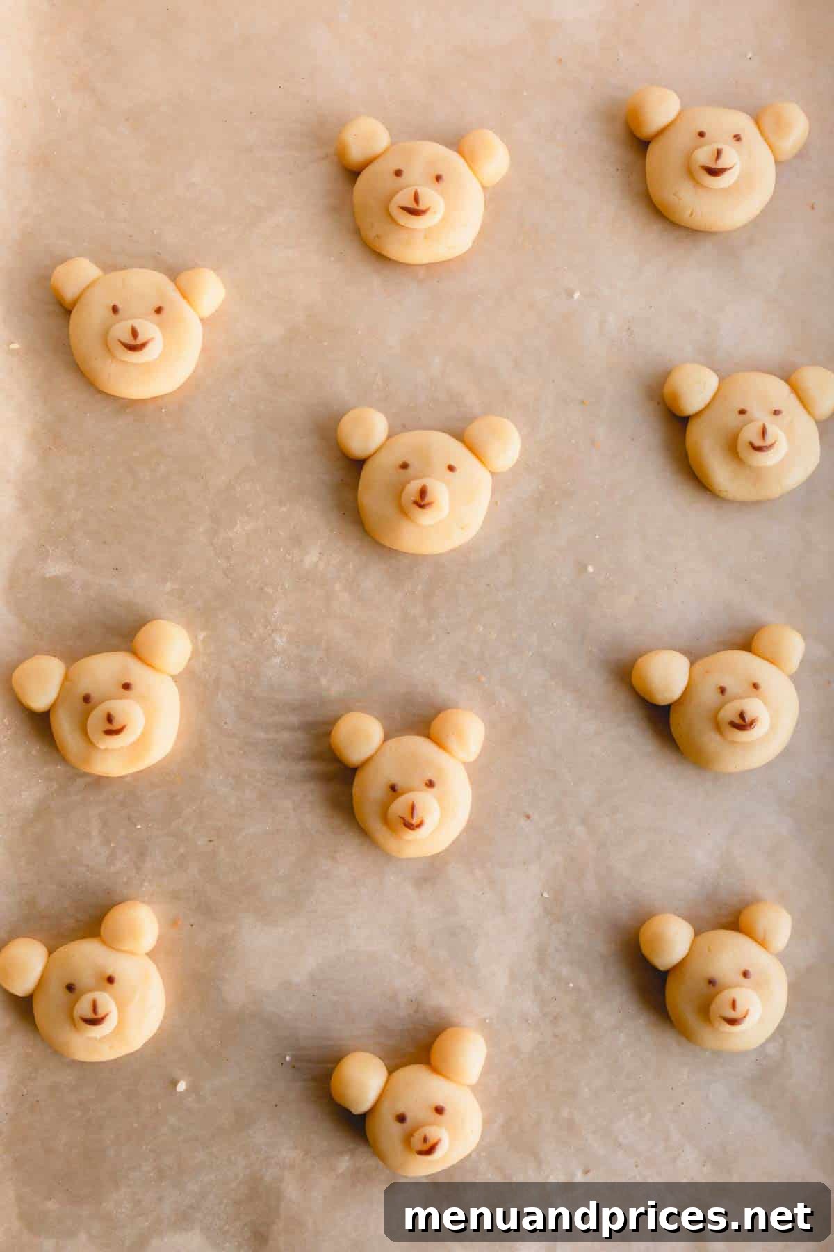 Unbaked teddy bear cookies on a baking sheet, showing the shaped dough.