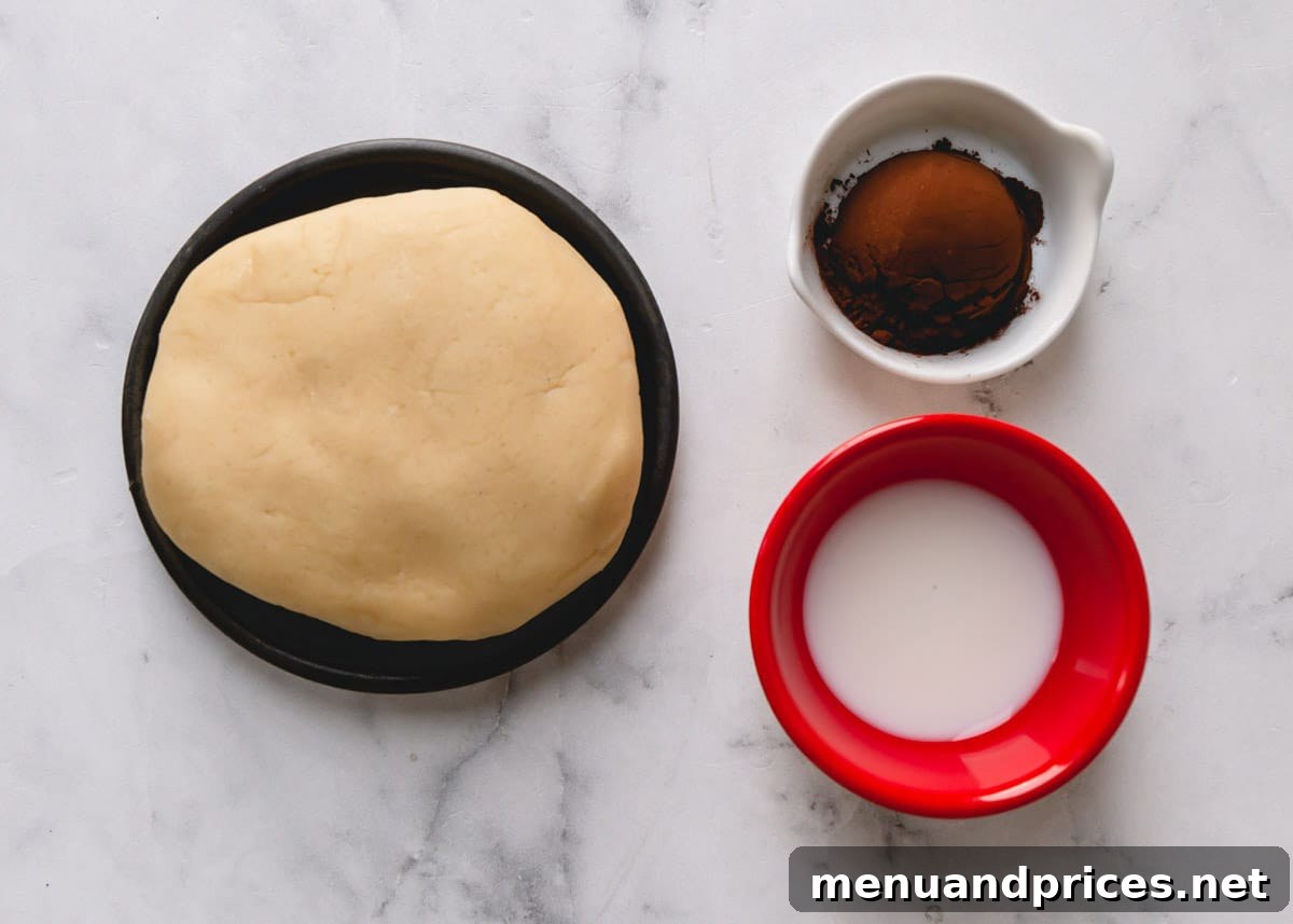 Cookie dough ball, cocoa powder, and milk, ingredients for chocolate cutout cookies.