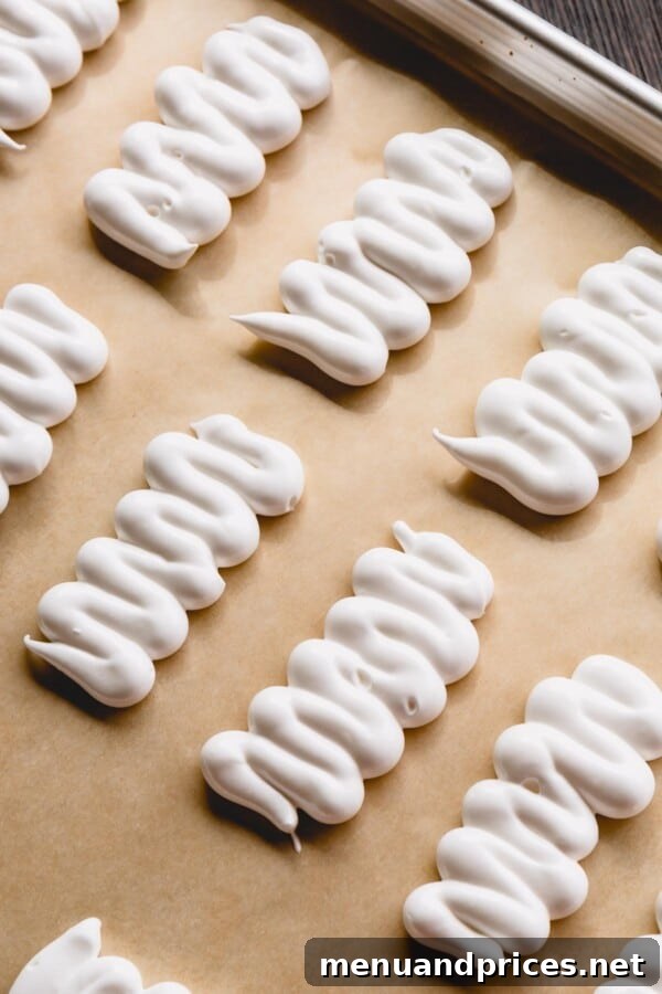 Bandaged Meringue Delights 4 A pristine white meringue mixture being carefully piped in a classic zigzag pattern onto a baking sheet, forming the distinct body of a mummy, ready for baking.