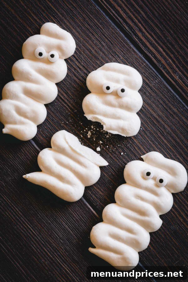 Bandaged Meringue Delights 5 A trio of delightful mummy meringue cookies, one thoughtfully broken to reveal its delicate, crunchy interior.