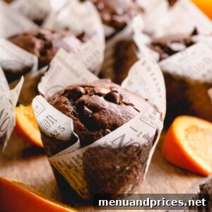 A perfectly baked double chocolate orange muffin, garnished with orange slices and chocolate chips.