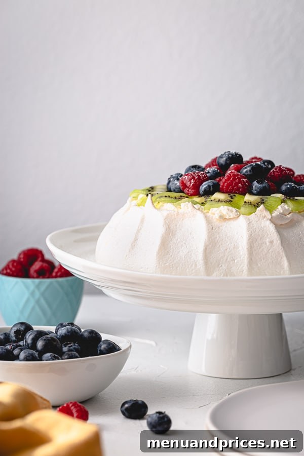 Effortless Pavlova Perfection 2 A beautifully garnished Pavlova cake, showcasing its crisp meringue, fresh whipped cream, and mixed berries, inviting a delightful dessert experience. #pavlovacake