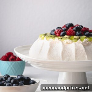 Effortless Pavlova Perfection 11 A classic Pavlova cake, generously topped with an array of fresh berries and rich whipped cream, presented as a delicious and elegant dessert. #pavlovacake