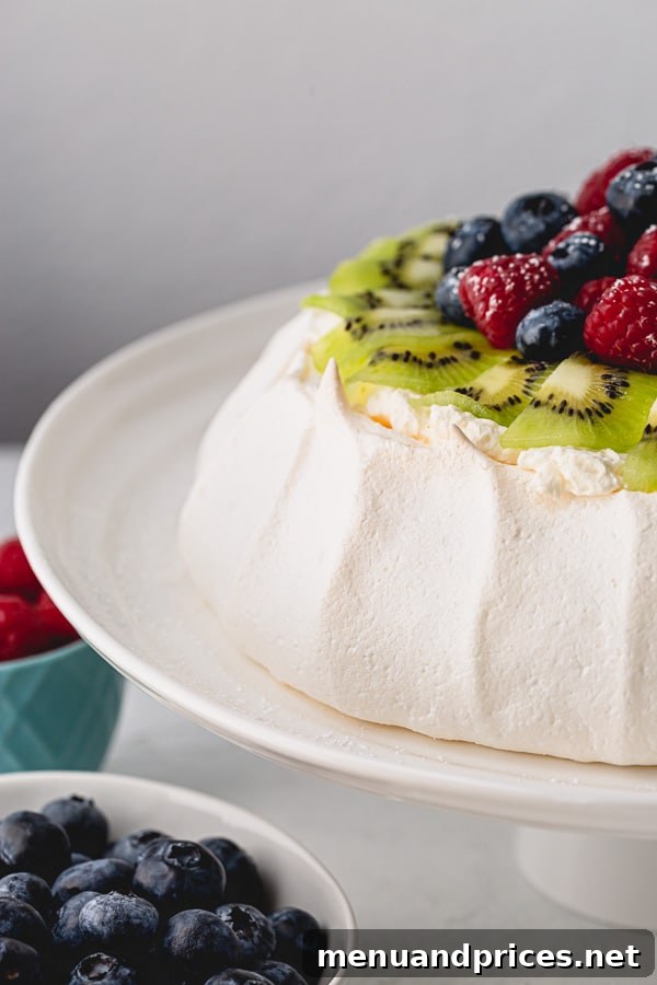 Effortless Pavlova Perfection 4 A close-up shot of a Pavlova slice, revealing its distinct crisp crust and soft, marshmallowy center, adorned with creamy topping and colorful fruits. #pavlovaflavors