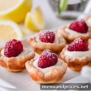 Raspberry lemon tartlets arranged on a rectangular serving platter, beautifully garnished.