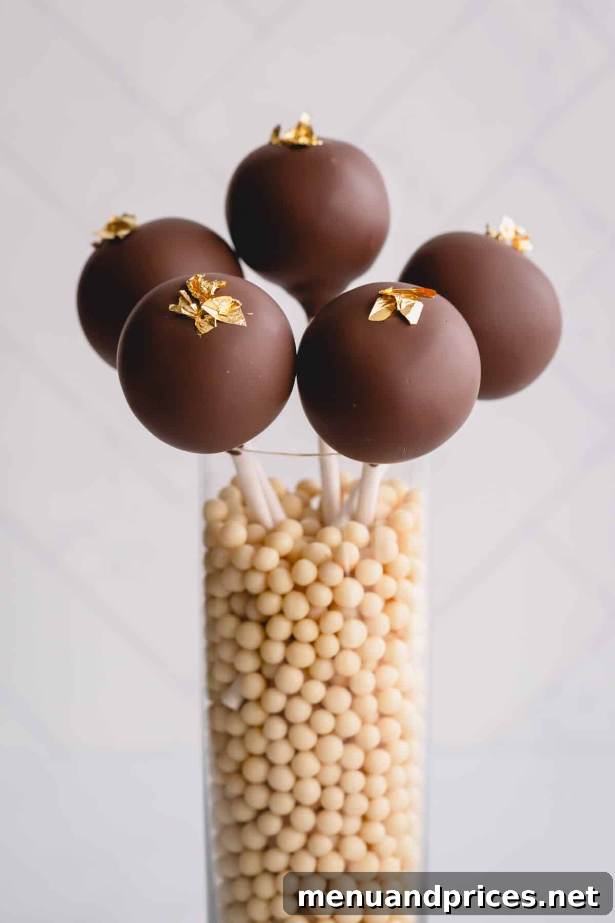 Crafting Perfect Chocolate Cake Pops From Scratch 3 chocolate cake pops in a jar of sugar pearls.