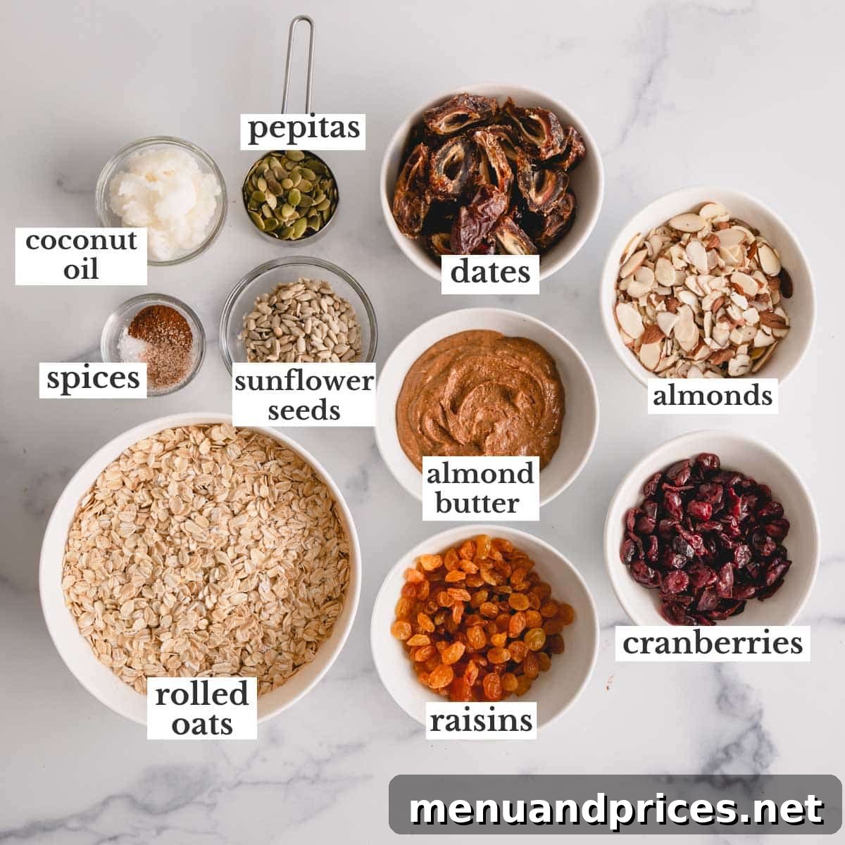 Wholesome Almond Crunch Granola 4 A collection of ingredients for homemade granola including oats, almond butter, coconut oil, various dried fruits, nuts, and seeds.