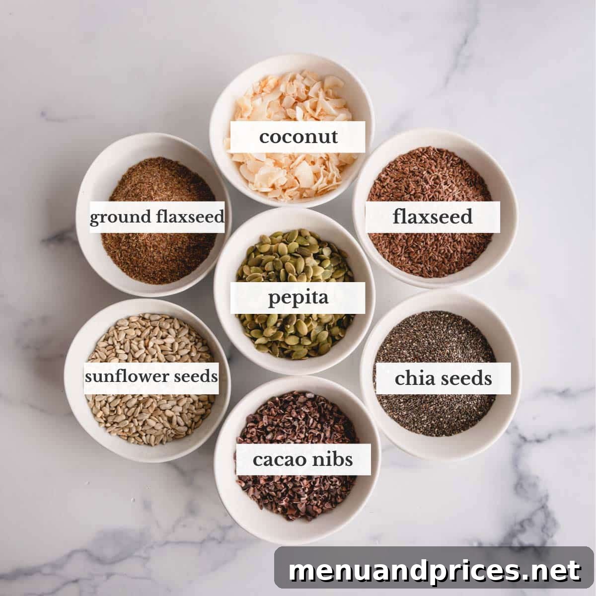 Your Complete Guide to Delicious Smoothies 5 A selection of healthy smoothie toppings, including shredded coconut, flaxseed, pepitas, sunflower seeds, chia seeds, and cacao nibs, arranged on a wooden background.