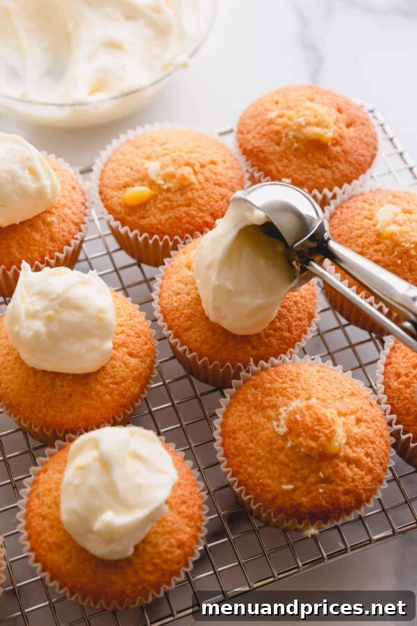 scooping frosting onto lemon cupcakes.