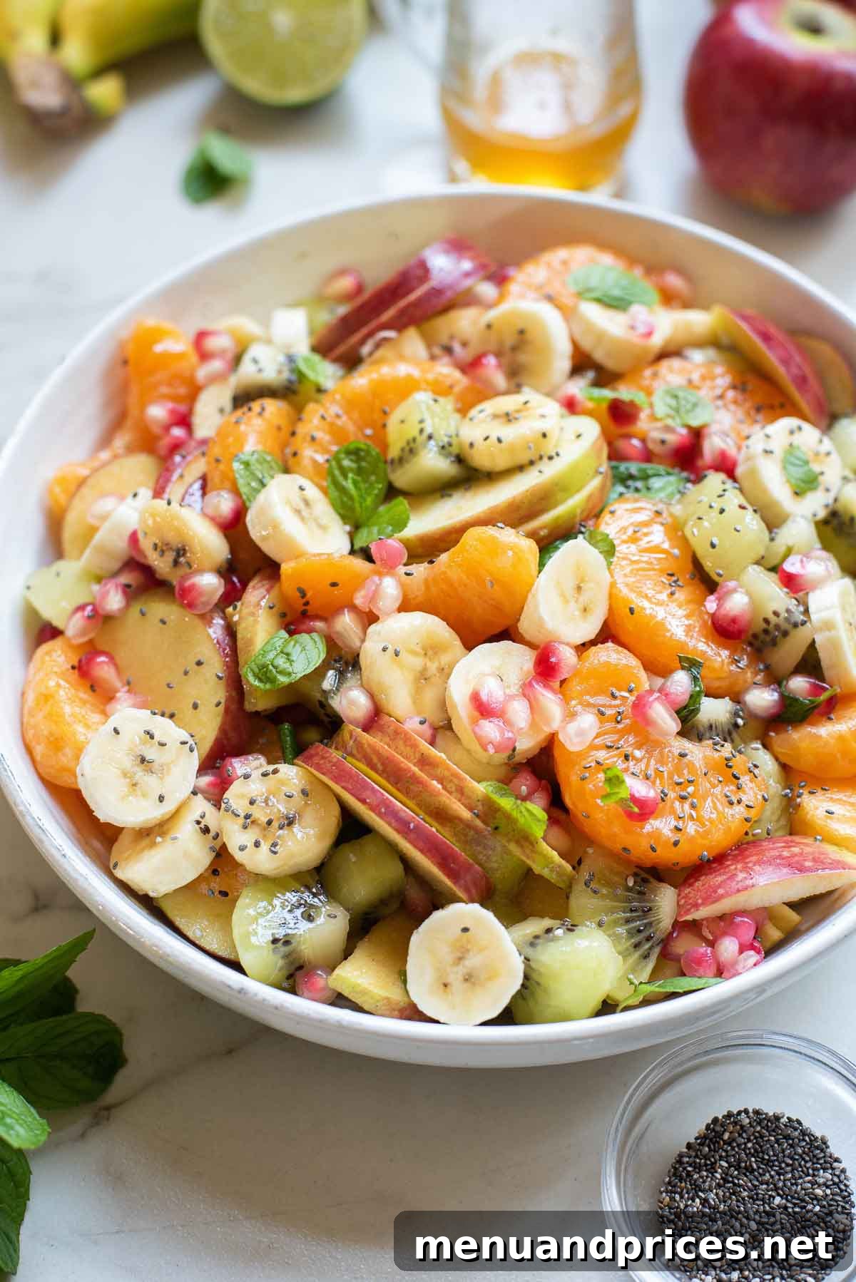A large bowl filled with a colorful mix of fresh fruit salad, glistening with honey lime dressing.