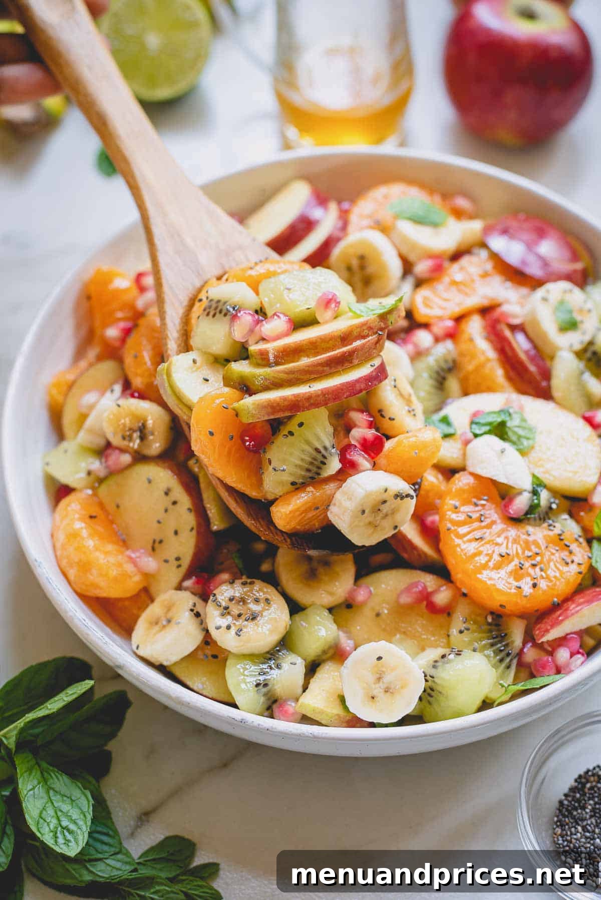 A large spoonful of the vibrant honey lime fruit salad being lifted from a bowl, showcasing the fresh fruit pieces.