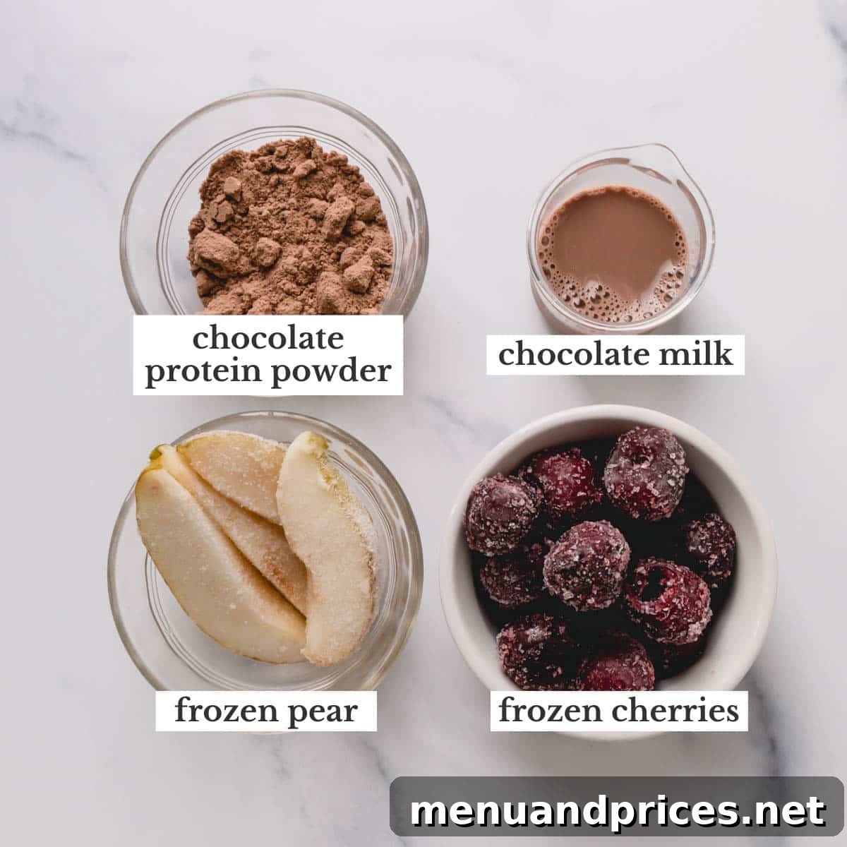 Black Forest Bliss Bowl 3 Individual ingredients for the Black Forest Smoothie Bowl: chocolate protein powder, chocolate milk, sliced frozen pear, and whole frozen cherries displayed on a surface.