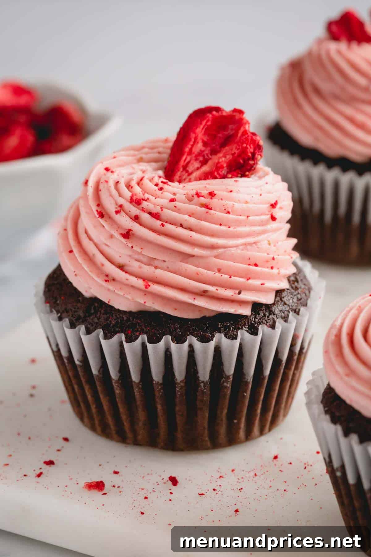 Velvet Strawberry Swiss Buttercream 2 Decadent chocolate cupcake adorned with a swirl of strawberry Swiss meringue buttercream and a fresh strawberry on top.