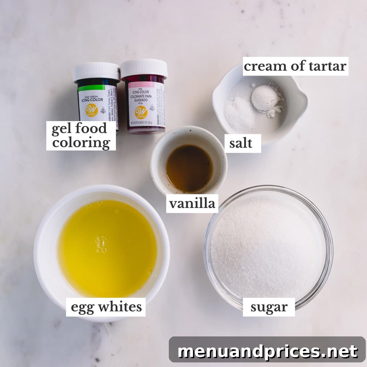 Effortless Meringue Delights 3 A collection of meringue cookie ingredients including egg whites, granulated sugar, pure vanilla extract, coarse kosher salt, cream of tartar, and colorful gel food coloring.